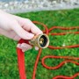 Main tenant un tuyau d'arrosage rouge avec raccord en aluminium doré sur fond d'herbe verte