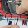 رجل يربط أسلاك كهربائية بأشرطة بلاستيكية سوداء داخل لوحة كهربائية