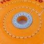 Détail central d'un disque de polissage en tissu orange avec couture renforcée et trou au centre