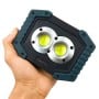 Projecteur portatif LED compact avec deux LEDs circulaires, tenu dans une main.