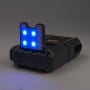 Booster batterie compact avec lumière LED bleue allumée et structure noire et orange sur fond gris.