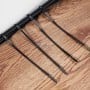 Colliers de serrage en plastique noirs disposés sur une surface en bois, avec différentes longueurs visibles.