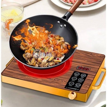 Plaque de cuisson électrique avec surface imitation bois, poêle en train de cuire des fruits de mer flambés