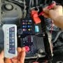 Testeur de batterie 12V avec affichage LED utilisé sur une batterie de voiture sous le capot.