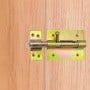 Verrou porte cadenas métallique jaune installé sur une porte en bois clair