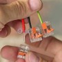 Main tenant trois connecteurs électriques rapides transparents avec fils rouge, noir et vert-jaune
