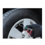 Main gantée utilisant un outil démonte valve sur la valve d'un pneu de voiture