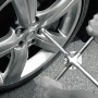 Personne utilisant un croisillon pour dévisser un écrou de roue sur une jante de voiture.
