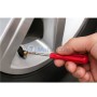 Clé démonte-obus avec manche rouge utilisée pour retirer un obus de valve de pneu sur une roue de voiture.