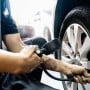 Un homme utilise une rallonge de valve flexible pour gonfler un pneu de voiture.